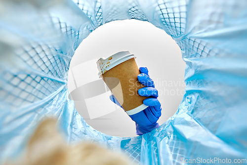 Image of female doctor throwing coffee cup into trash can