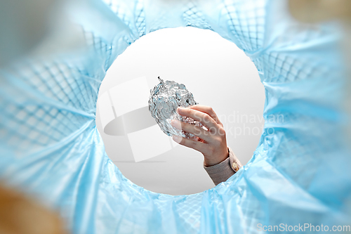 Image of hand throwing crumpled foil into trash can