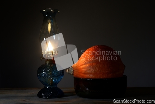 Image of orange Hokkaido pumpkin in a ceramic bowl and a burning oil lamp