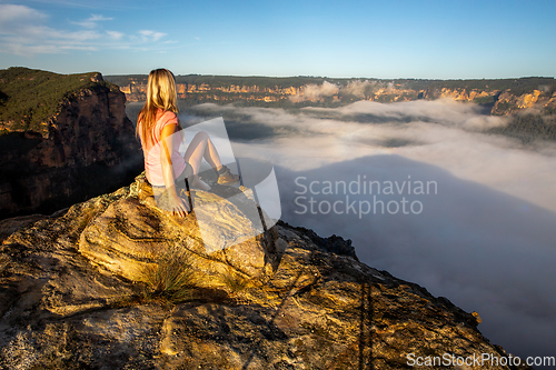 Image of Woman hiker sitting high in mountain taking in magnificent views