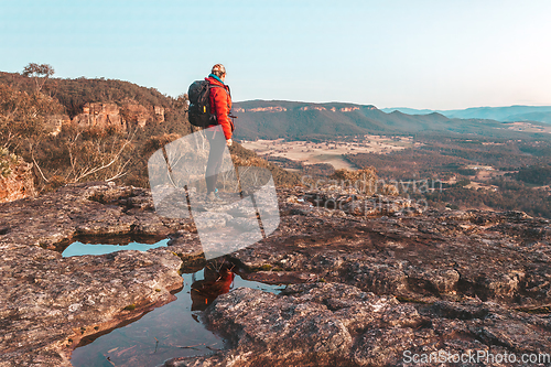 Image of Female hiker at to the top of a rugged cliff face overlooking a