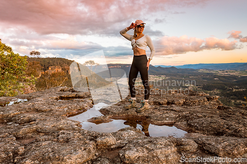 Image of Female standing on a rock plateau as the sun sets