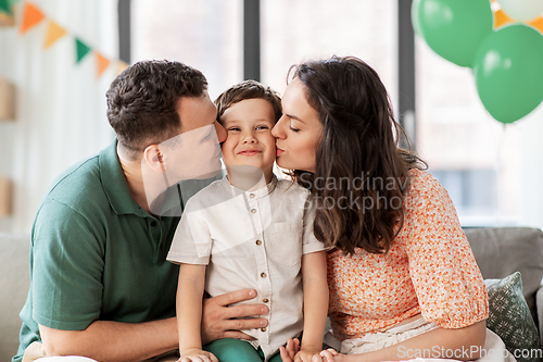 Image of happy parents kissing little son at birthday party