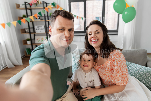 Image of happy family taking selfie on birthday at home