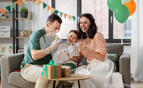 Image of happy family with gifts and party blowers at home