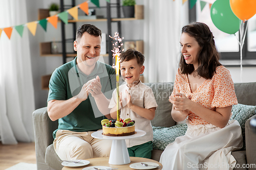 Image of happy family with birthday cake at home