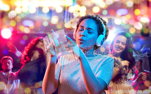 Image of woman in headphones dancing at nightclub