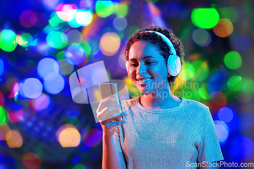 Image of woman in headphones with smartphone in neon lights