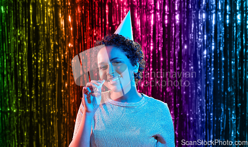 Image of african woman in party cap with blower over black