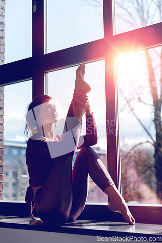 Image of woman doing yoga exercise on window sill at studio