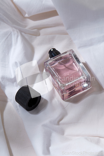 Image of bottle of perfume and cap on white sheet