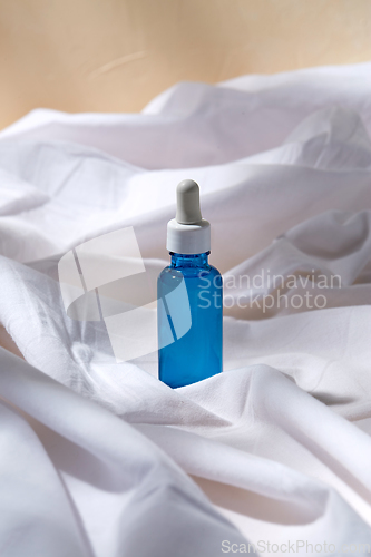 Image of bottle of serum on white sheet