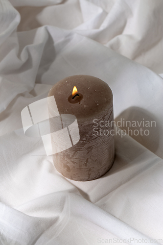 Image of burning aroma candle on white sheet