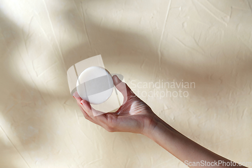 Image of hand holding bar of craft soap on beige background