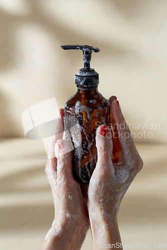Image of hands with bottle of shower gel or liquid soap