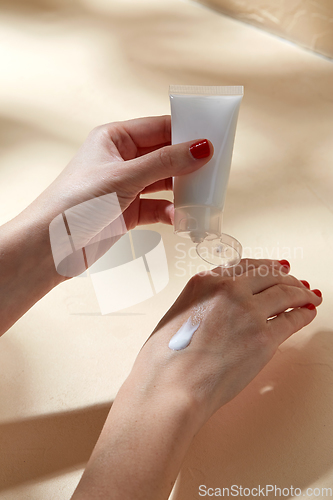 Image of female hands applying moisturizer to skin