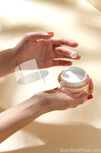 Image of female hand holding jar of moisturizer