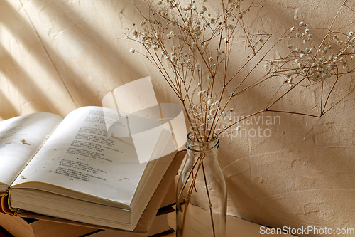 Image of books and decorative dried flowers in glass bottle