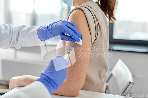 Image of female doctor with syringe vaccinating patient