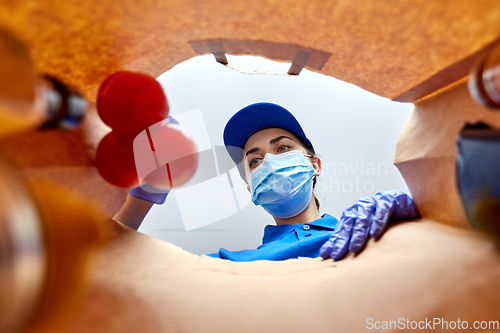 Image of delivery girl in gloves and mask with food in bag