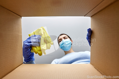 Image of woman in mask taking cleaning supplies from box