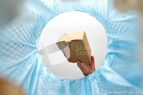 Image of hand throwing paper box into trash can