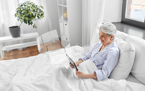 Image of senior woman with tablet pc in bed at home bedroom