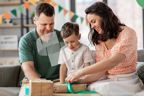 Image of happy family opening birthday presents at home