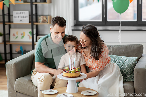 Image of happy family with birthday cake at home