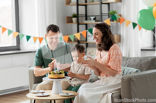 Image of happy family with birthday cake at home