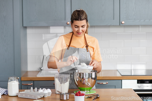 Image of happy young woman cooking food on kitchen at home