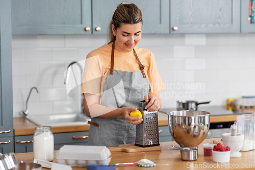 Image of happy young woman cooking food on kitchen at home