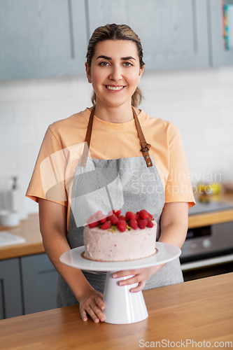 Image of happy woman with raspberry cake on kitchen at home