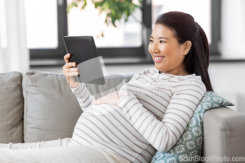 Image of happy pregnant asian woman with tablet pc at home