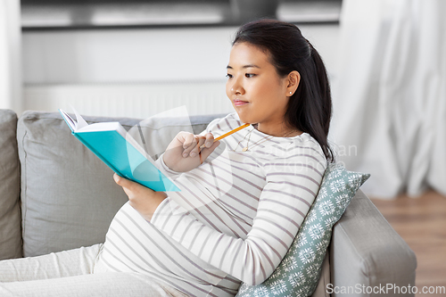 Image of pregnant woman writing to diary at home