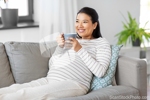 Image of happy pregnant woman drinking tea at home