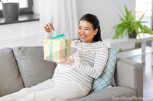 Image of happy pregnant woman with gift box at home