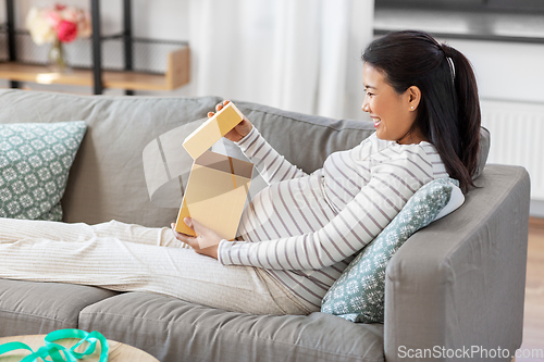 Image of happy pregnant woman opening gift box at home