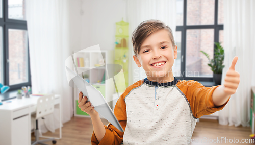 Image of smiling boy with tablet showing thumbs up at home