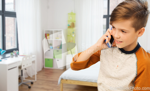 Image of happy boy calling on smartphone at home