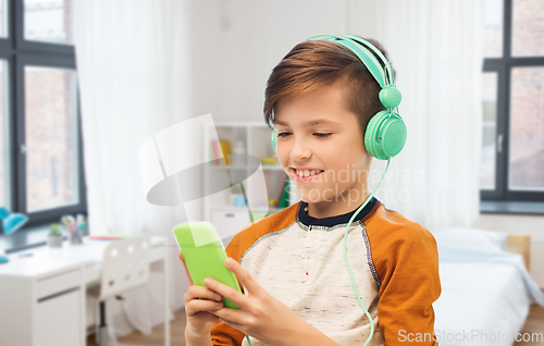 Image of happy boy with smartphone and headphones at home