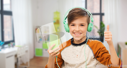 Image of happy boy with smartphone and headphones at home