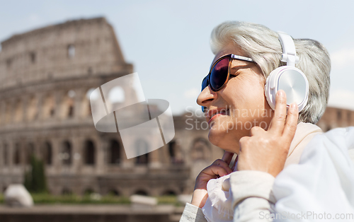 Image of old woman in headphones listens to music in rome