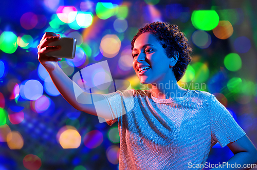 Image of woman taking selfie with smartphone in neon lights