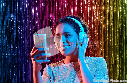 Image of woman in headphones with smartphone at party