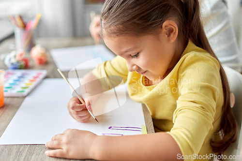 Image of little girl drawing picture with colors and brush