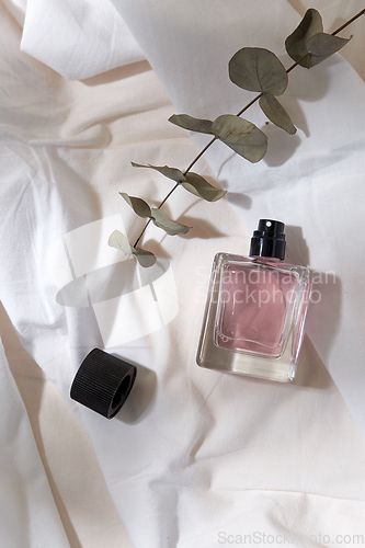 Image of bottle of perfume and on white sheet