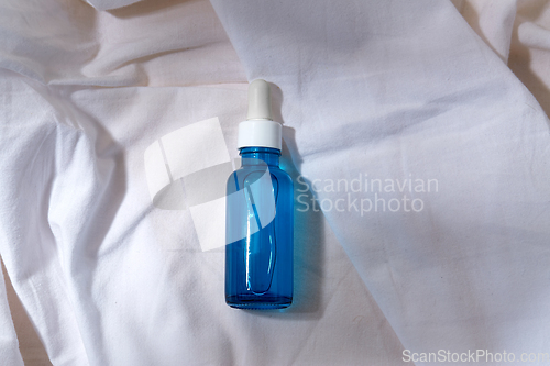 Image of bottle of serum on white sheet