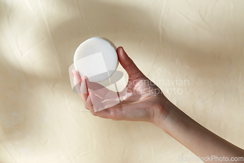 Image of hand holding bar of craft soap on beige background