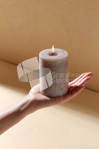 Image of hand holding burning aroma candle on palm